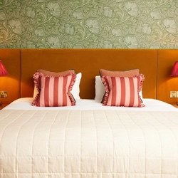 A double hotel room bed with cushions, bed side tables and lamps at The Dog and Partridge.