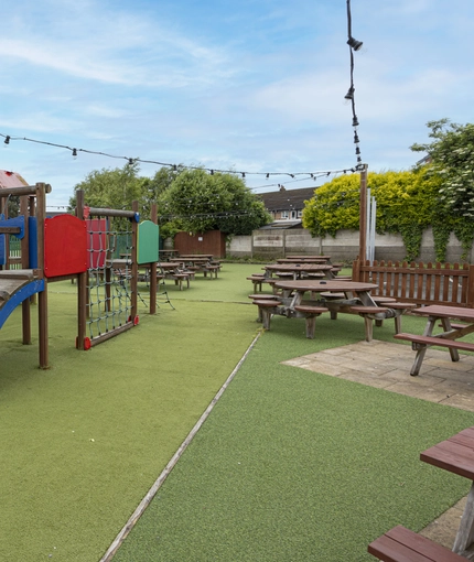 Exterior play area and beer garden of a pub with a seating area.