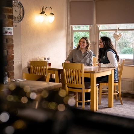 Two Women sat at a table smiling 