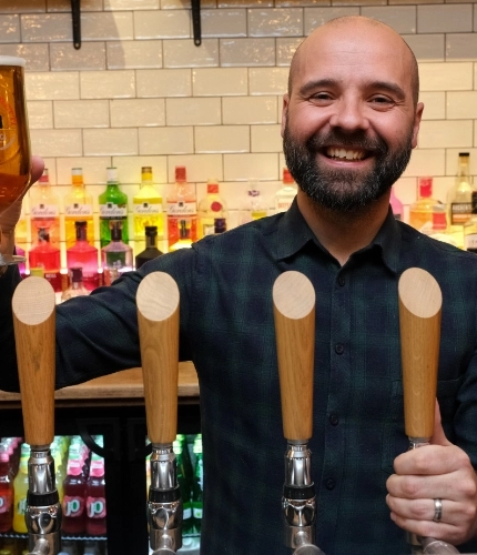 A team member and a pint of beer at the bar