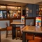The bar and interior restaurant seating area at The Heron in Havant; with wooden tables, upholstered chairs, and bar stool seating.