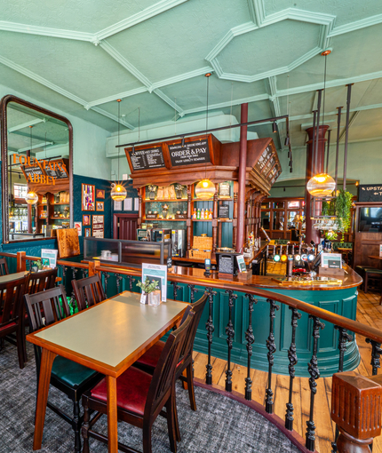 The bar and interior restaurant seating area of The Fountains Abbey, with TVs on the walls and a raised seating section with wooden railings.