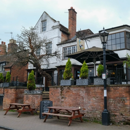 The exterior facade, signage and seating areas of The Dirty Duck, with steps leading up to the entrances.