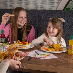 Two children enjoying kids meals served at a Flaming Grill venue.