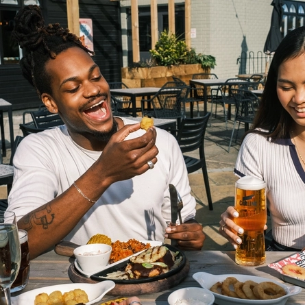 Friends enjoying a meal and drinks in the exterior seating area and beer garden from the new Spring/Summer menu at Flaming Grill.