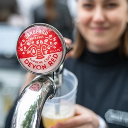 An image focusing on a pint of cider being poured by a member of staff stood behind the exterior bar during The Boat Race event at The Crabtree.