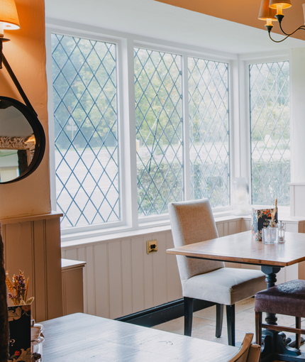 The interior restaurant seating area of The Green Man, with framed artwork and mirrors on the wall, and wooden beams.