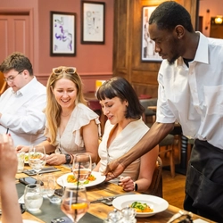 A group of people being served food within the interior restaurant seating area during The Durell Arms launch party.