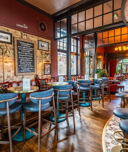The interior bar with bar stool seating and restaurant seating area with tables, chairs, cushioned seating and exposed brickwork at The Duke Of Sussex.