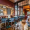The interior bar with bar stool seating and restaurant seating area with tables, chairs, cushioned seating and exposed brickwork at The Duke Of Sussex.