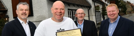A team picture with Tom holding a plaque for 20 years outstanding service at The Hand & Flowers.