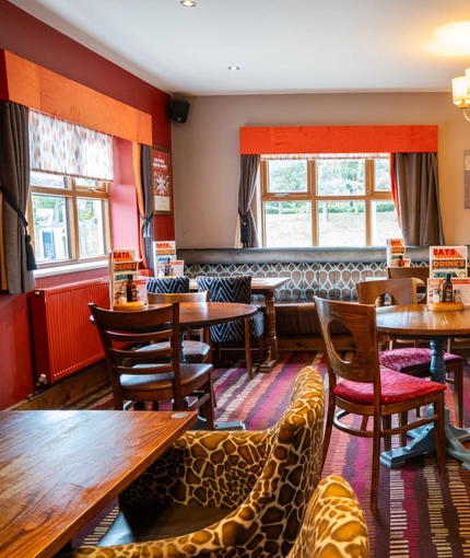 The interior restaurant seating area of The Royal Horse, with wooden tables and upholstered seats.