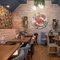 The interior restaurant seating area at The Royal Oak in Bishops Cleeve; with wooden flooring, an upholstered booth seat along one wall, and artificial flowers hanging on the wall and ceiling.