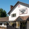 The exterior facade, signage, seating area, and car park of The Bramford Arms in Woodsetton, with accessible parking spaces near the entrance, and a ramp leading up to the double doors.