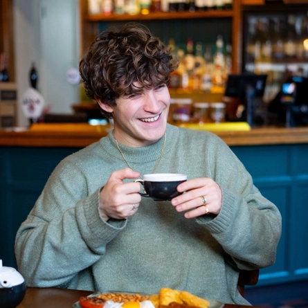 An image focusing on a person sat with a group of people at a table within the restaurant area with a breakfast dishes and drinks available at Urban Social venues.