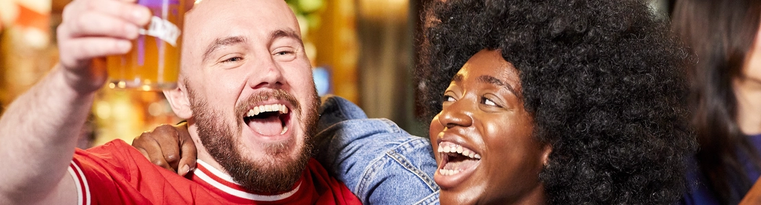 Two people holding a drink and cheering.