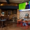 An interior restaurant seating area at The Royal Oak; with wooden flooring, a log burner in a large stone fireplace, and a TV on the wall.