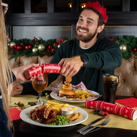 An interior shot of people celebrating Christmas and enjoying festive food in the restaurant/seating area at a Flaming Grill venue.