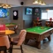 The interior games area at the Devonshire Arms in Sheffield, with two pool tables, a dartboard, TVs on the walls, and restaurant seating.