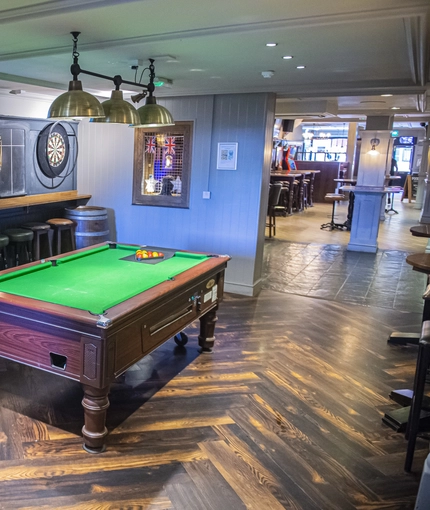 Interior seating area with Pool table, dart board and TV showing football