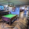Interior seating area with Pool table, dart board and TV showing football