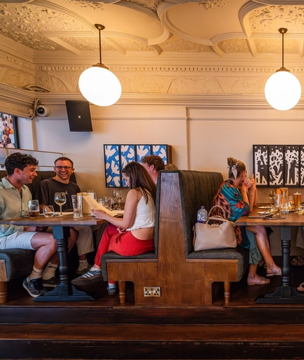 A group of people enjoying drinks within the interior restaurant seating area during The Durell Arms launch party.