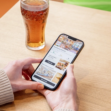 Hands holding a mobile phone displaying the Farmhouse Kitchen order screen.