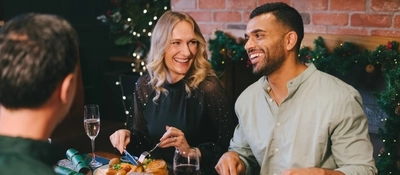 An image of a group of friends enjoying plated Festive mains and various drinks within the interior restaurant seating area of an Urban Core venue.