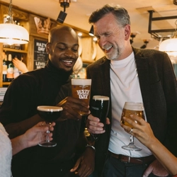 Group at a pub bar holding an espresso martini, a Hazy Day beer, a pint of Guinness and a glass of beer.