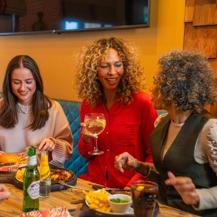 A mixed group of people seated at an indoor table enjoying a meal.