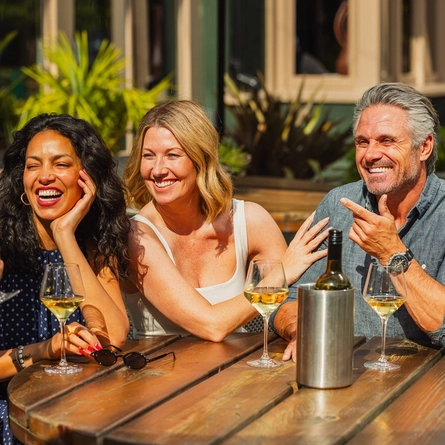 An image of people enjoying white wine within the exterior beer garden seating area at a Crafted venue.