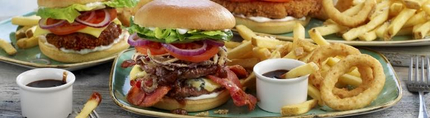 Three plates of burger, chips and onion rings