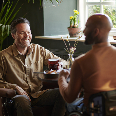 A father and son sitting at a table with food in front of them.
