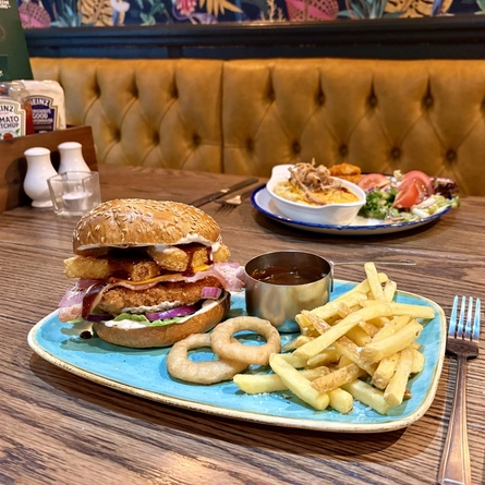 Plated dishes for Burger of the Month October served at Greene King Pubs.  One is a roasting dish of Macaroni Cheese and a plated chicken burger.