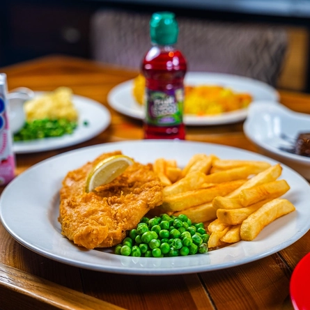 A plate of fish and chips on a table at a Hungry Horse.