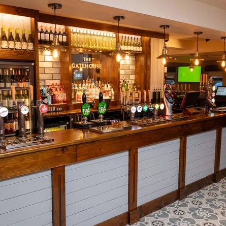 A close up view of the bar at The Gatehouse, with bottles of wine and alcoholic spirits on shelves behind the counter.