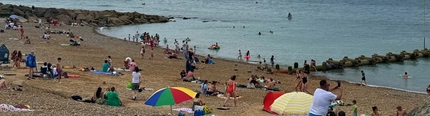 An image of a beach with people under sun umbrellas.