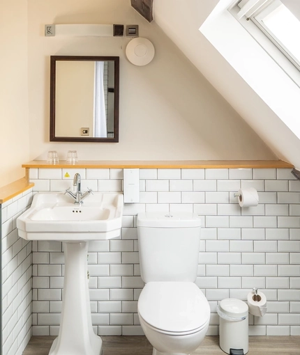 An ensuite bathroom with bath and overhead shower at The Red Lion, Adderbury.