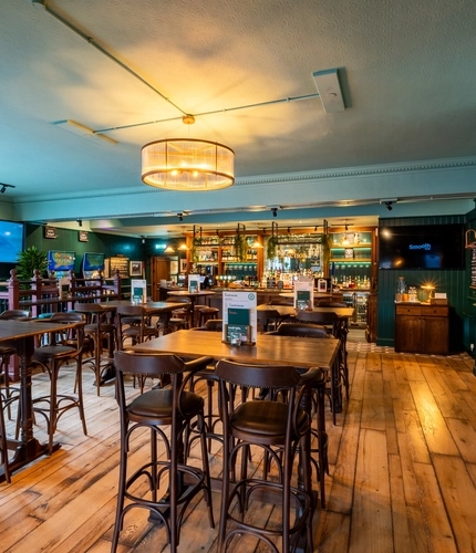 The bar and interior restaurant seating area at The Junction in Upminster, with TVs on the walls, and gaming machines.