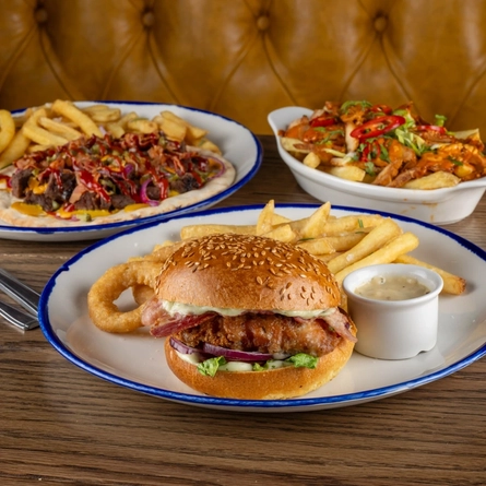 A selection of June Burger of the Month dishes on an indoor table.