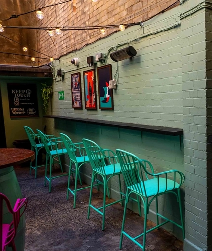 The exterior seating area at Adam & Eve in St James, with framed artwork on the walls, and string lights overhead.
