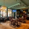 The interior restaurant seating area at the Phoenix in Bayswater, with TVs on the walls, a gaming machine, and a wooden staircase leading to the upper floor.