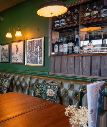 An image focusing on two of the tables within the interior restaurant seating area with tables, chairs, cushioned seating and Specials advertising chalkboard at The Spice Island.