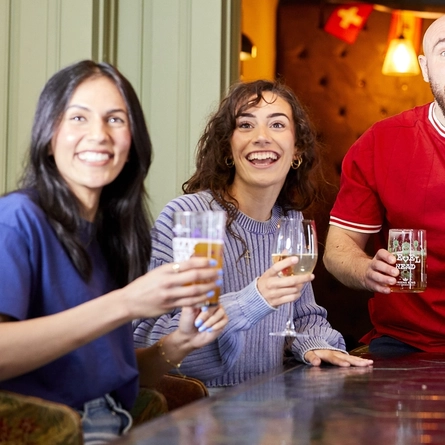 A mixed group of people, sitting at an indoor table reacting to sport event.