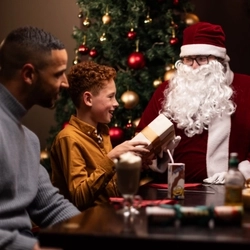 A family laughing and exchanging presents at breakfast with Santa.