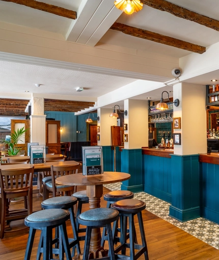 The bar and interior restaurant seating area at The Walkford, with wooden beams on the ceiling.
