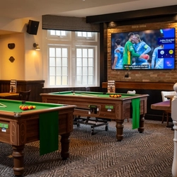 The interior pub gaming area of The Railway, with two pool tables, a TV on the wall, and restaurant tables.