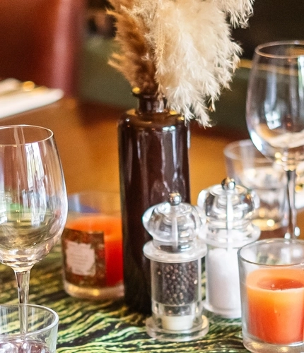 A close up image of the table decor featuring cutlery, glasses and peacock design table runner within one of the function rooms at The Vine.