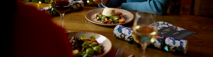 An image of 2 people enjoying 2 dishes and 2 glasses of wine within the interior restaurant seating area at a Chef & Brewer venue.