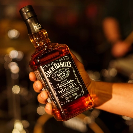 A hand holding a bottle of Jack Daniels.